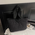 Detailopname van zwarte gewatteerde nylon shopper met golfpatroon en merklabel aan zijkant - Zwart
