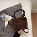 Braune Beuteltasche mit geflochtenem Griff und goldenem Markenlogo in Lifestyle-Szene - Kaffeebraun