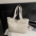 Detail van gewatteerde shopper in gebroken wit met golvende stiksels en ritszak aan de voorkant - Off-wit