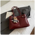 Dettaglio della borsa tote bordeaux in pelle lucida pieghettata con fibbie e ciondolo orso - Rosso Vino con Ciondolo