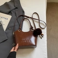 Detail of vintage brown leather bucket bag featuring letter embossing and fur pom pom charm - With Pendant / Brown