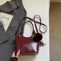 Detail view of burgundy PU leather bucket bag with debossed logo and brown fur ball charm - With Pendant / Burgundy