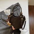 Detail view of small dark brown suede bag with knotted handle and star charm accessory - With Pendant / Coffee