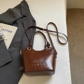 Brown leather bucket bag with embossed letters and golden ring handle in a stylish setup - No Pendant / Burgundy
