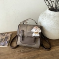 Detailopname van de retro bruine rugzak met puppy-hanger en geruit sierlint - Koffie met Hanger