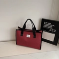 Detalle del bolso tote de cuadros rojos mostrando la textura de la tela y las asas negras - Rojo