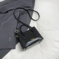 Dettaglio ravvicinato di una borsa a secchiello nera in finta pelle con trama a coccodrillo - Nero