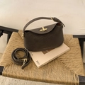 Detail van donkerbruine leren handtas met gouden draaisluiting op vintage stoel - Bruin