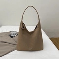 Detail of khaki suede leather hobo bag with embossed logo on a white fabric background - Khaki