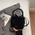 Detailed close-up of a black suede bucket bag featuring a woven chain handle and gold logo - Black