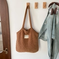 Detail der braunen Lammfell-Tragetasche mit SEEYOU-Label an einem weißen Wandhaken - Braun