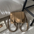 Detalle del bolso tote de cuero camello con hebillas metálicas y logo en entorno hogareño - Estilo Solapa Vintage (1107588) / Caqui