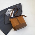 Detail van de stiksels van karamel suède en donkerbruin leer op de bucket bag - Geelbruin