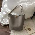 Détail du sac seau en cuir gris avec fermoir rotatif doré et logo de marque embossé - Sans Pendentif / Gris