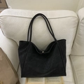 Minimalist black large capacity matte leather tote bag for women on a beige sofa - Black