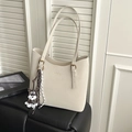 Detail of off-white tote bag with golden logo, puppy charm, and luxury hardware finish - White With Pendant