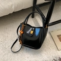 Detail der schwarzen Bucket Bag mit Goldverschluss und dekorativem Holzperlen-Anhänger - Schwarzes PU-Leder