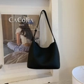 Close-up of black litchi pattern leather hobo bag with silver buckle on a wall - Black