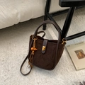 Detail der braunen Wildleder-Beuteltasche mit Lederboden und dekorativer Holzperlen-Quaste - Wildleder Kaffee