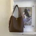 Détail du sac seau en cuir grainé marron avec fermoir tournant doré et pendentif tressé - Avec Pendentif / Marron