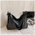 Close-up of black hobo bag with vintage texture next to a laptop on white fabric - Black