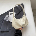 Schicke cremeweiße Hobo-Tasche mit silberner C-Schnalle auf grauem Blazer-Hintergrund - Cremeweiß