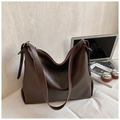 Detail of dark brown leather tote bag with adjustable strap in a cozy desk setting - Brown