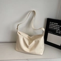 Primer plano del bolso hobo crema con herrajes dorados y textura lisa minimalista - Blanco