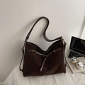 Detail einer dunkelbraunen Tasche aus mattem Wildleder mit Vintage-Beschlägen und Trageriemen - Braun