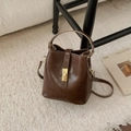Dettaglio della borsa a secchiello in pelle cerata marrone con fibbia dorata e texture - Sabbia