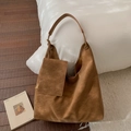 Detail einer tan-wildleder Hobo-Tasche mit passendem Mini-Etui auf weißem Kissen - Braun