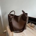 Detalle del bolso tote minimalista en cuero granulado marrón oscuro con correa larga - café
