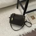 Dettaglio della borsa in pelle opaca marrone scuro con rivetti dorati e parti metalliche - Caffè Scuro