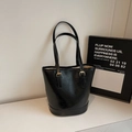 Detalle de bolso tote retro negro con textura arrugada brillante y hebilla de metal dorado - Negro