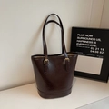 Detalle de bolso tote de cuero engrasado marrón oscuro con correa fina ajustable - café
