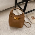 Elegante warm bruine lederen emmer tas met gouden sluiting op een wit pluche tapijt - Bruin Zonder Hanger