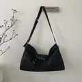 Detalle de un bolso tote grande de ante negro con correa decorativa y ojales de metal plateado - Negro