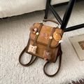 Detalle de mochila retro marrón con lazo de cuadros rojos y lindos dijes de peluche - Marrón