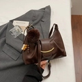 Detailansicht der braunen Leder-Beuteltasche mit Faltenoptik und weichem Pelzball-Anhänger - Mit Anhänger / Kaffeebraun