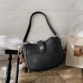 Detail of black pebbled leather bucket bag with silver buckle and plush charm on rattan chair - Black (With Charm)