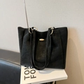 Minimalist black leather tote bag with gold oval hardware on white display props - No Pendant / Black