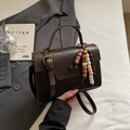 Borsa a tracolla in pelle marrone scuro con chiusura dorata e ciondolo in perle di legno - caffè
