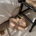 Elegant beige leather bucket bag with silver metal clasp in a stylish indoor setting - Khaki
