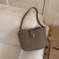 Minimalist taupe lychee leather bucket bag with silver metal buckle on a cozy sofa - Gray