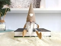 Detail eines gestrickten Weihnachtswichtels mit Kaffeetasse, der auf Büchern sitzt - Khaki Männlich