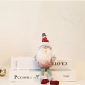 Gebreide Kerstman met rood gestreepte muts en krullende baard op witte decoratieve boeken - Kerstman