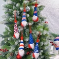 Set of six festive USA patriotic gnomes hanging as ornaments on a snowy Christmas tree - Red Rope Style