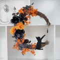 Halloween-Mondsichelkranz mit orangefarbenen Blumen und schwarzer Katzen-Silhouette - Orange