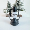 Detail of Halloween skeleton lantern keychain with black frame and metal ring on snowy background - Skull Lantern