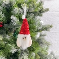 Dettaglio di gnomo natalizio in peluche con cappello di paillettes appeso all'albero - Babbo Natale Rosso